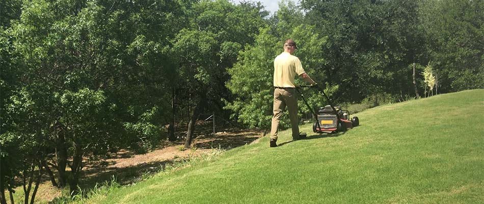 Lawn care worker mowing a yard with a push mower in Keller, TX.